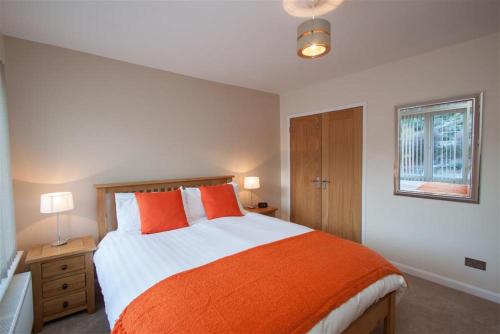 - une chambre avec un grand lit et des oreillers orange dans l'établissement Beckside, à Ambleside