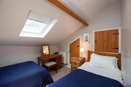 - une chambre avec 2 lits, un bureau et une lucarne dans l'établissement Lowfold Cottage, à Ambleside