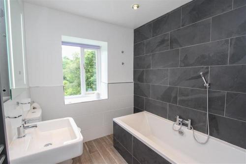 a bathroom with a white tub and a sink at Elterwater Lodge in Little Langdale