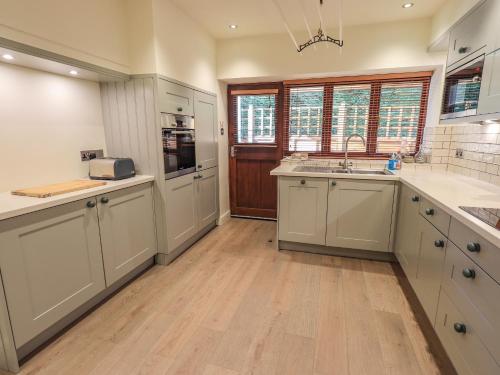 a large kitchen with white cabinets and wooden floors at Croft in Grasmere