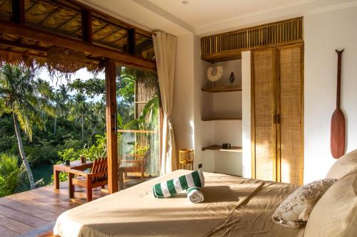 a bedroom with a bed and a large window at The River Hideaway in General Luna
