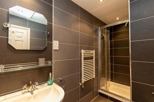 uma casa de banho com um lavatório, um chuveiro e um espelho. em Windermere Suite em Ambleside