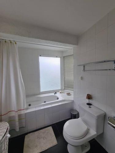 a bathroom with a toilet and a tub and a window at Gran casa en Totoralillo con vista al mar y más! in Coquimbo