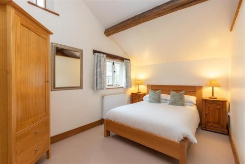 a bedroom with a large white bed and a window at Forest Cottage in Coniston