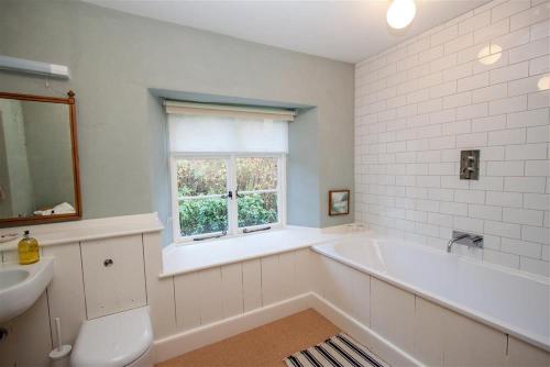 bagno con vasca, lavandino e finestra di Thomas Grove House a Penrith
