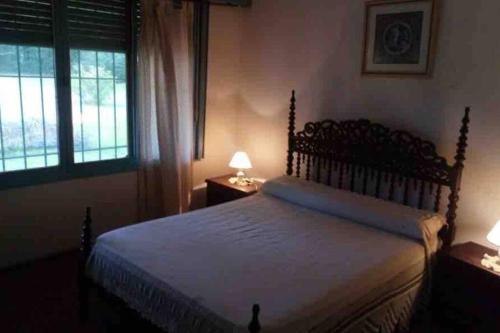 a bedroom with a bed with two lamps and a window at Quinta con pileta in Diego Gaynor