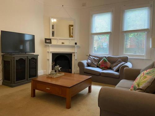 a living room with a couch and a tv and a table at Central CBD House in Wagga Wagga