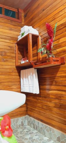 a bathroom with a wooden wall with a shelf and towels at Jardin entre Montañas in Bijagua