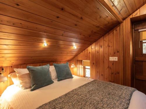 a bedroom with a bed in a wooden wall at Dovecot Cottage in Ambleside