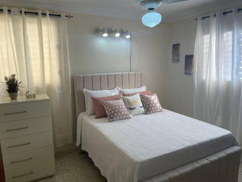a bedroom with a bed with pillows and a dresser at MView: Comfortable, great location, city view in Santiago de los Caballeros