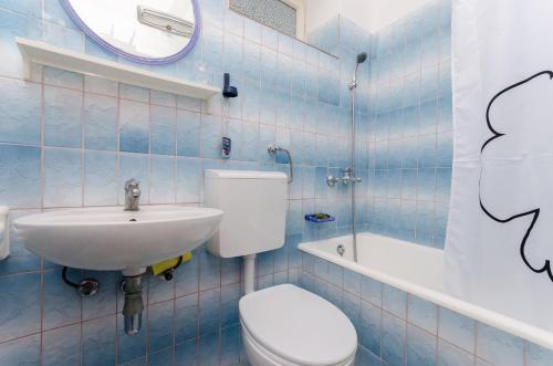 a blue tiled bathroom with a toilet and a sink at Rooms Sonja P in Rab