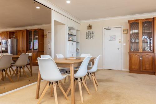 a dining room with a wooden table and white chairs at Shoreline 7 with 180 degree water views in Tuncurry