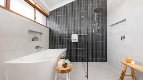 a bathroom with a tub and a shower with black tiles at Sunset at The Moorings in Soldiers Point