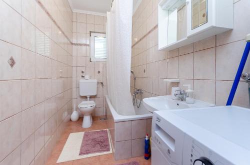 a bathroom with a sink and a toilet and a tub at Apartments Marija P Lopar in Lopar