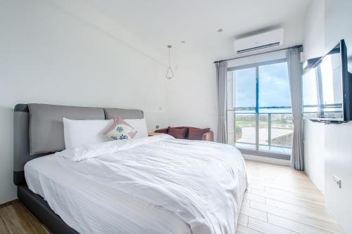 a bedroom with a white bed and a large window at Wenshui in Jiaoxi