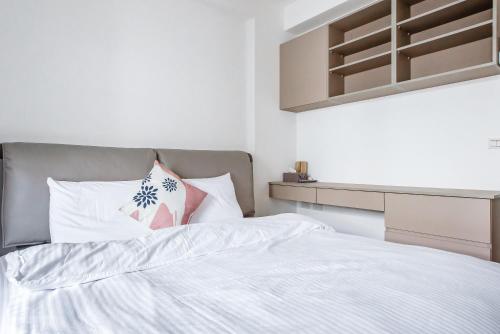 a bed with white sheets and a pink pillow at Wenshui in Jiaoxi