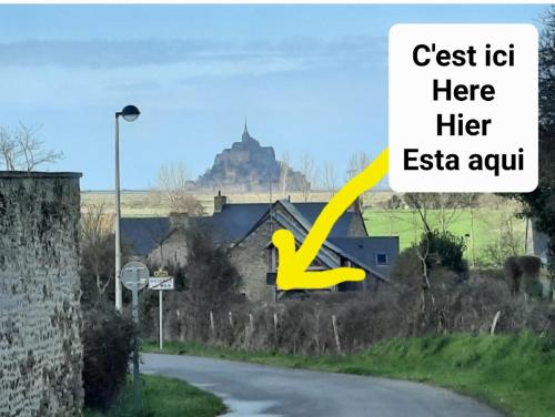 a house on a road with a hill in the background at Le Canari in Huisnes-sur-Mer