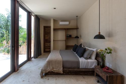 a bedroom with a large bed and a large window at Unho Tulum in Tulum