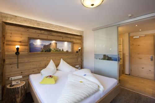 a bedroom with a white bed with a picture on the wall at Kinderhotel Laderhof in Ladis