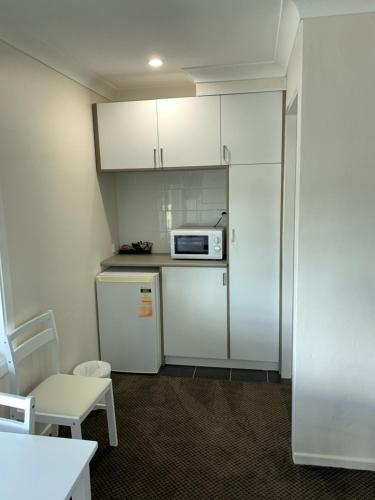 a small kitchen with a refrigerator and a microwave at Altona Motel in Uralla