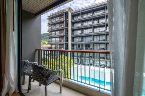 a balcony with two chairs and a view of a building at Panan Krabi Resort in Ao Nang Beach