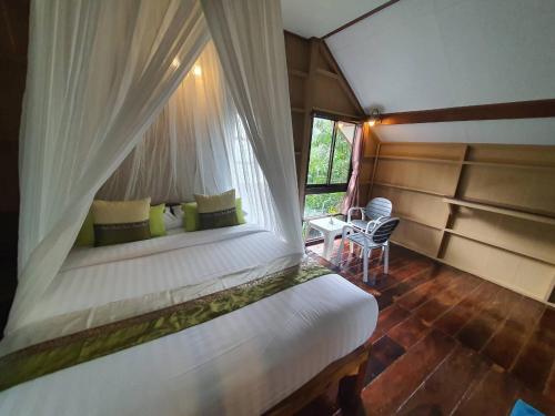 a bedroom with a bed in a room with a window at Malulee KhaoSok Resort in Khao Sok