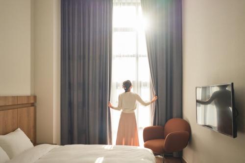 a woman looking out the window of a hotel room at Space and Mood in Busan