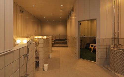盛岡市にあるホテルマザリウムの白いタイルの壁と長い廊下が特徴のバスルーム