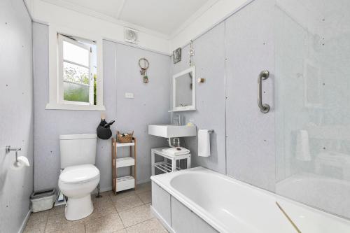 a bathroom with a tub and a toilet and a sink at The Shack in Woorim