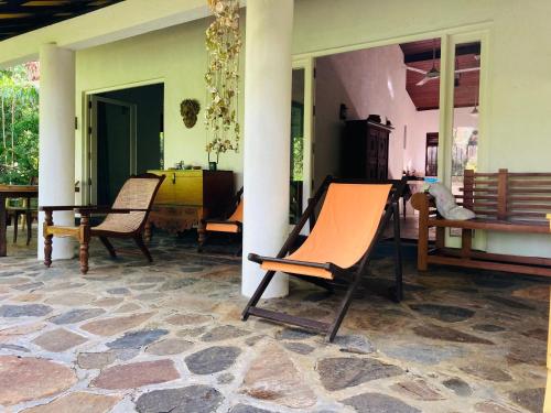 a room with chairs and a table on a patio at Whispering House in Tangalle