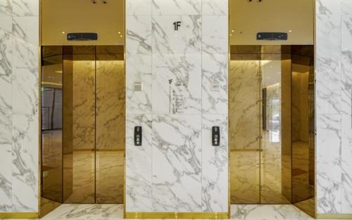 a lobby with four elevators with marble walls and mirrors at Busan Myeongji Ciel Ocean Hotel in Busan