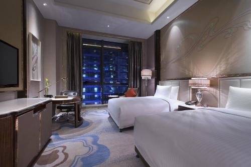 a hotel room with two beds and a desk and a window at Wanda Vista Lanzhou in Lanzhou