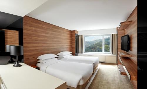 a hotel room with three beds and a television at Grand Walkerhill Seoul in Seoul