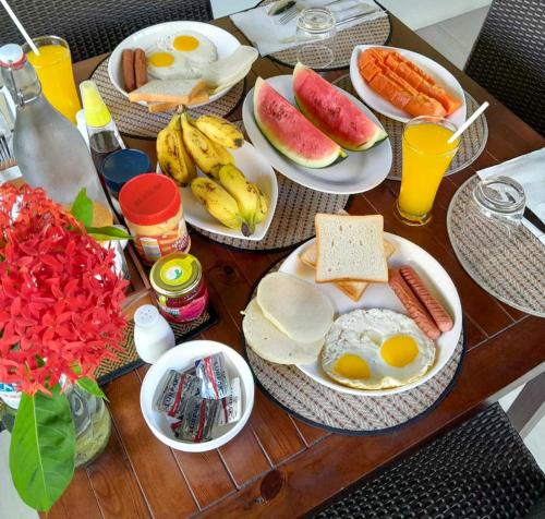 a table topped with plates of breakfast foods and fruit at Tides Dhigurah in Dhigurah