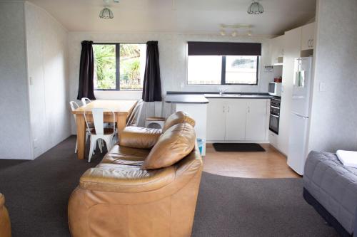 a living room with a leather couch and a kitchen at Whanganui Seaside Holiday Park in Whanganui