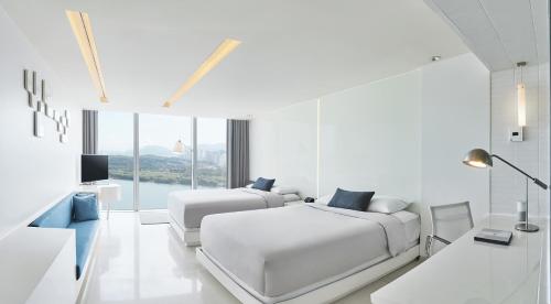 a white bedroom with two beds and a tv at Vista Walkerhill Seoul - formerly W Seoul in Seoul