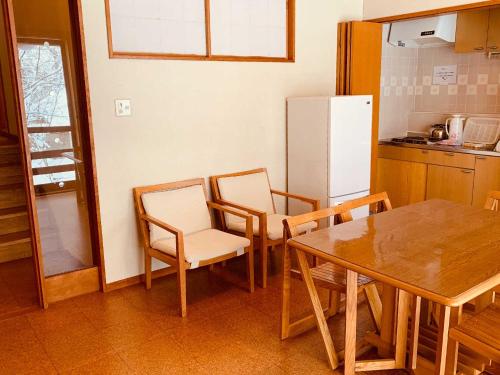cocina con mesa, sillas y nevera en Labo Land Kurohime, en Shinano