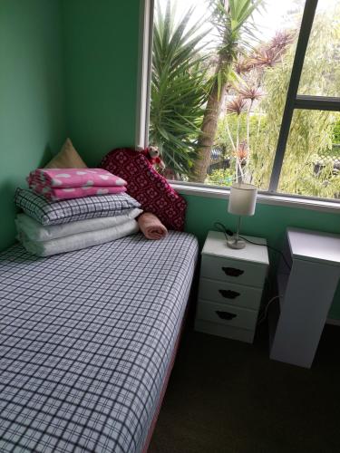 a small bedroom with a bed and a window at Wendy's Holiday Home in Auckland