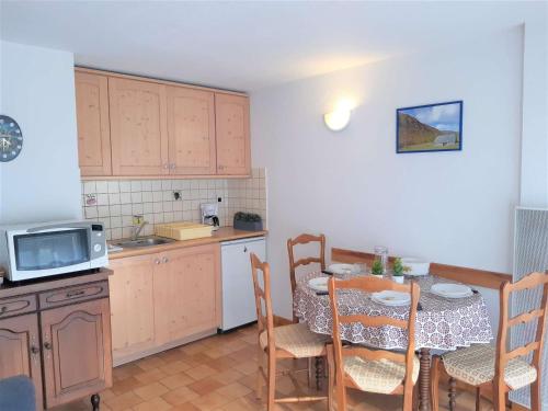 une cuisine avec une table, une table et un four micro-ondes dans l'établissement Appartement T2 à Saint-Lary pour 6 personnes avec balcon, exposition sud, parking et casier à skis - FR-1-457-189, à Saint-Lary-Soulan