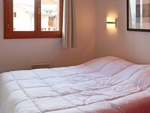 un lit blanc dans une chambre avec une fenêtre dans l'établissement Appartement cosy avec piscine, 4 pers, Les Orres 1800 - FR-1-322-432, aux Orres