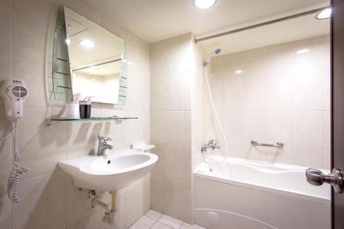 a bathroom with a sink and a shower and a tub at New World Hotel in Taipei