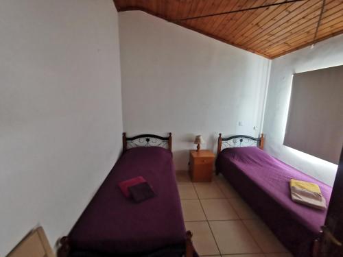 two beds in a room with purple sheets at Strovolos rooms Studios in Nicosia