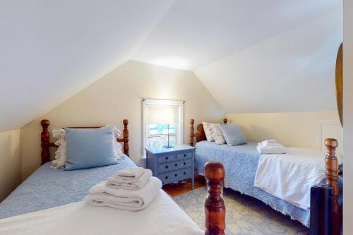 a attic bedroom with two beds and a mirror at Wisteria Cottage in Camden