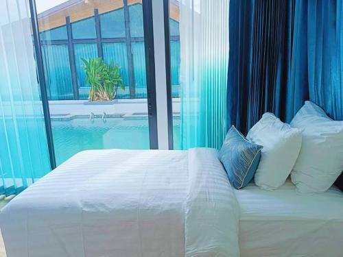 a white bed with pillows and a window with a pool at Southern Airport Hotel Hatyai in Hat Yai