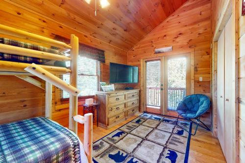 a bedroom with a bunk bed and a tv in a cabin at Bear Essentials in Sevierville