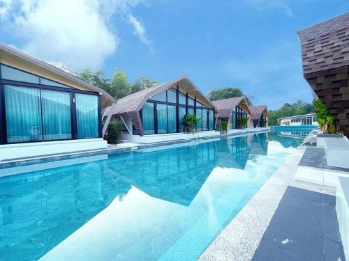 a swimming pool with blue water and glass buildings at Southern Airport Hotel Hatyai in Hat Yai