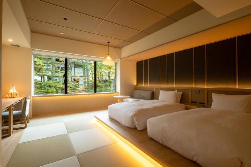 a bedroom with two beds and a window at Urakusatsu TOU in Kusatsu