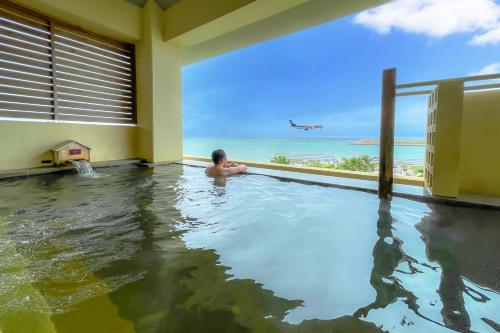 a man in a swimming pool with the ocean in the background at Senagajima Island Resort & Spa in Tomigusuku