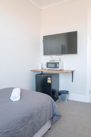 ein Schlafzimmer mit einem Bett und einem Flachbildfernseher in der Unterkunft Seven Seas Hotel in Carrington