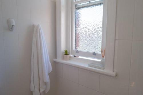 a white bathroom with a window and a towel at Seven Seas Hotel in Carrington